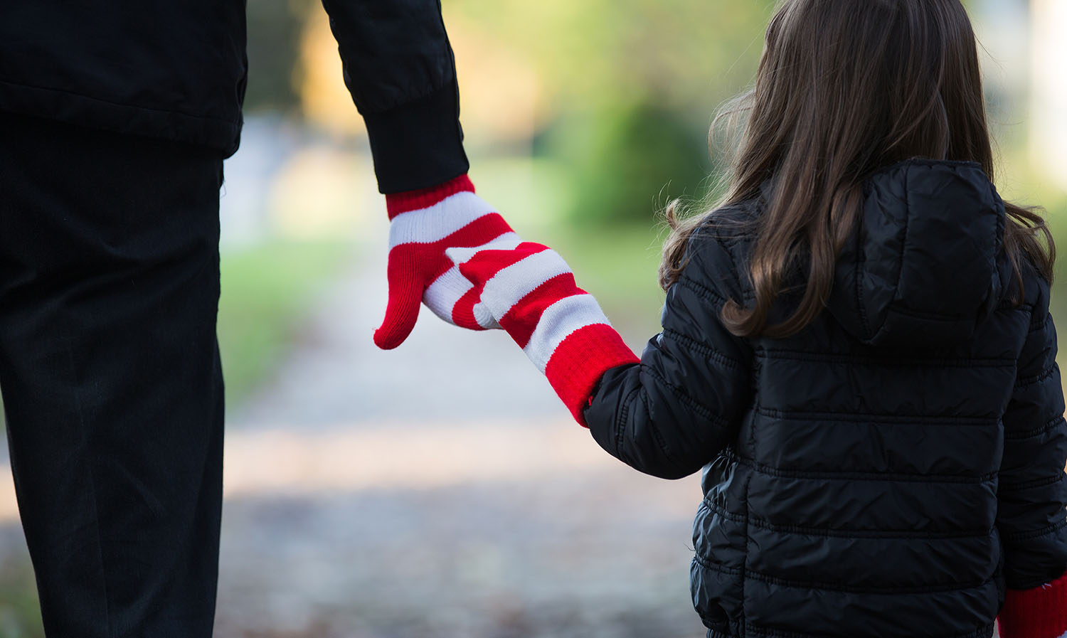 Adult and child holding hands wearing red and white striped gloves